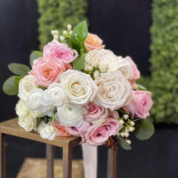 Bouquet of pink and white roses with greenery on a stand