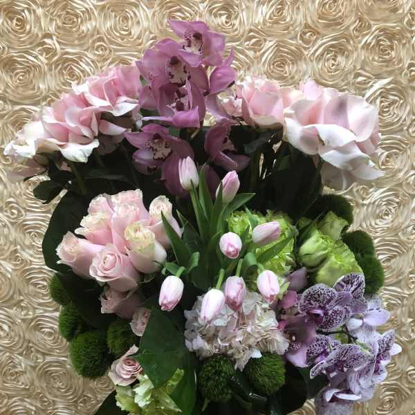 Pink and purple floral arrangement in a tall glass vase