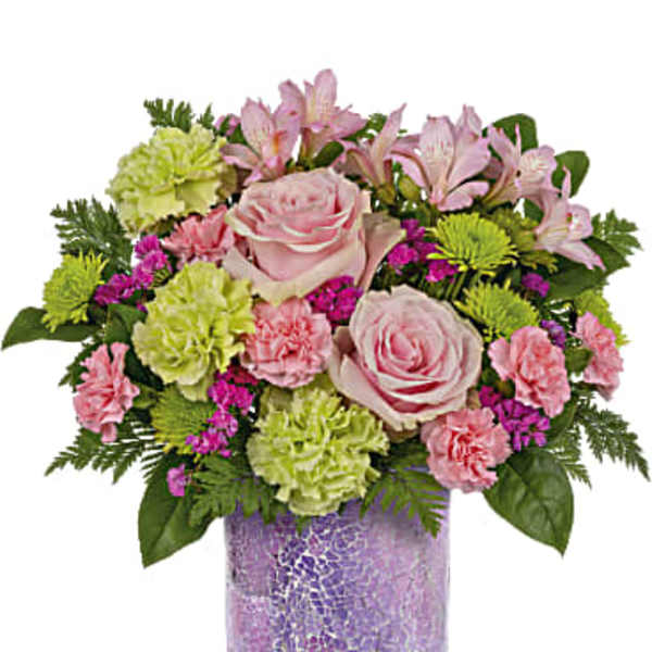 Pink roses and mixed flowers arranged in a purple glass vase