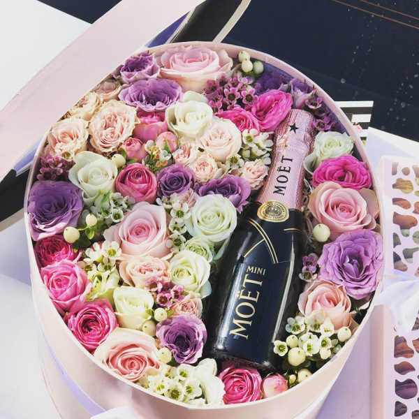 Round box of pink, purple, and white roses with a mini Moet bottle