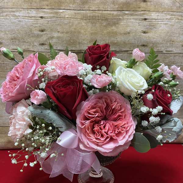 Pink and red rose bouquet in a clear glass vase with baby's breath