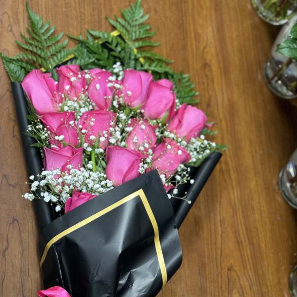 Bouquet of pink roses wrapped in black paper with a pink ribbon