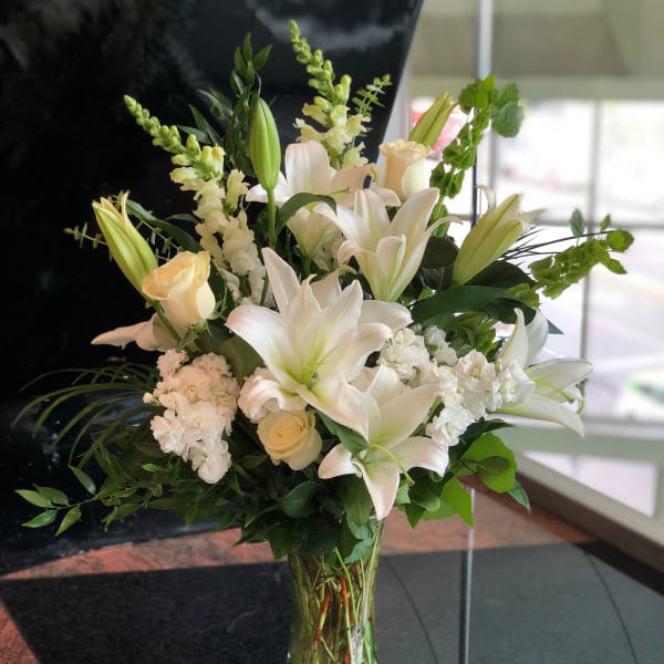 White lilies and cream roses in a clear glass vase