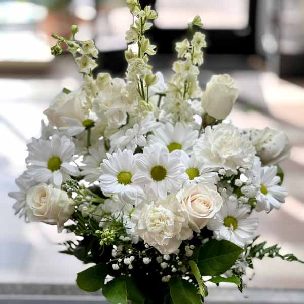 White bouquet of daisies and roses in a clear glass vase