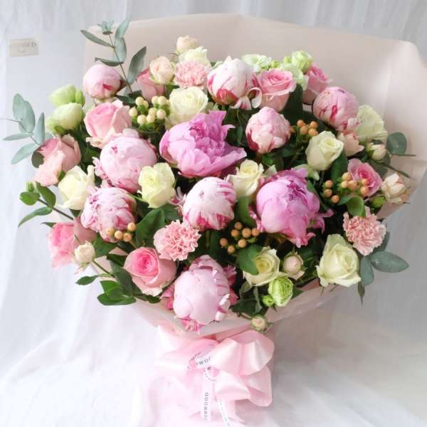Bouquet of pink and white peonies and roses with a pink ribbon