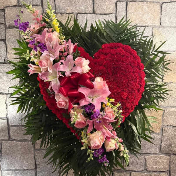 Heart-shaped floral spray with pink lilies and roses on a stand
