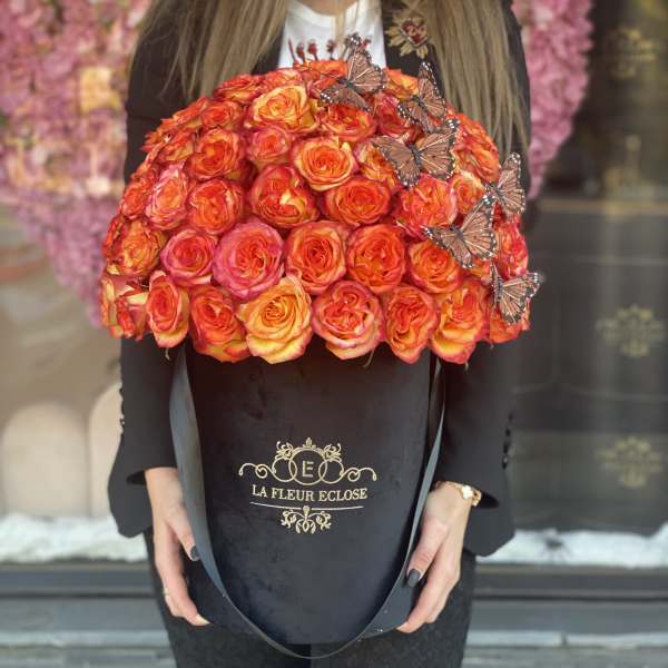 Large dome bouquet of orange and pink roses with butterfly accents