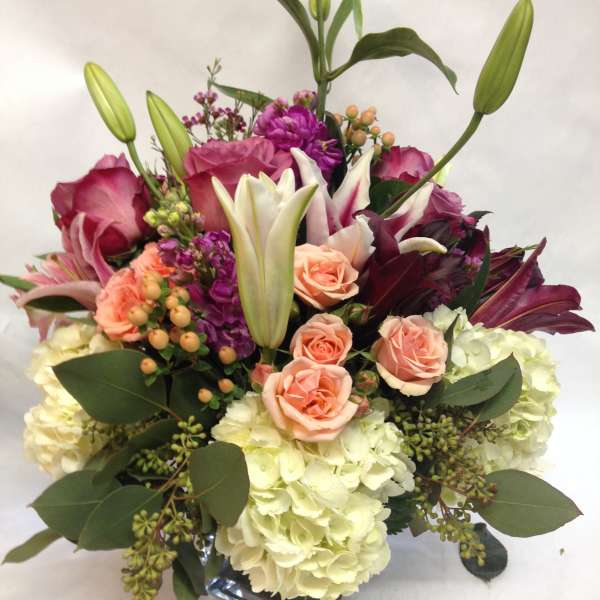 Bouquet of pink roses, lilies, and hydrangeas in a glass vase
