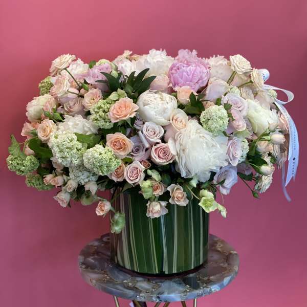 Large pastel bouquet in a striped green vase on a round table