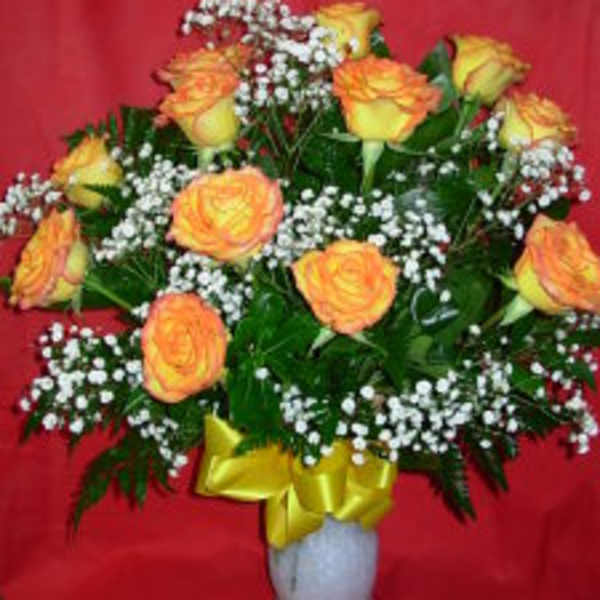 Yellow-orange roses with baby's breath in a white vase