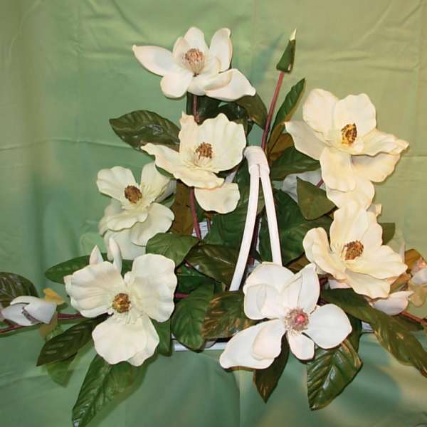 White magnolia-like flowers arranged with glossy green leaves on a green backdrop.