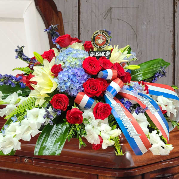 Red, white, and blue floral spray on a casket with ribbons