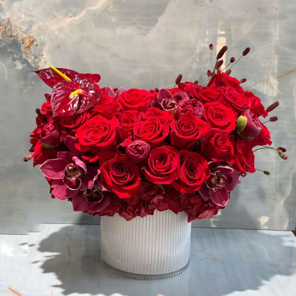 Red rose and orchid arrangement in a ribbed glass vase