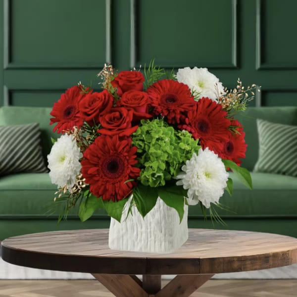 Red roses and gerbera daisies in a white vase with white blooms