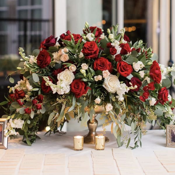 Large red and white rose arrangement in a gold vase on a table