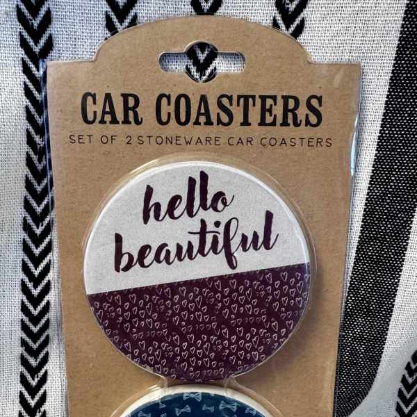 Packaged set of two round car coasters with printed text and patterns