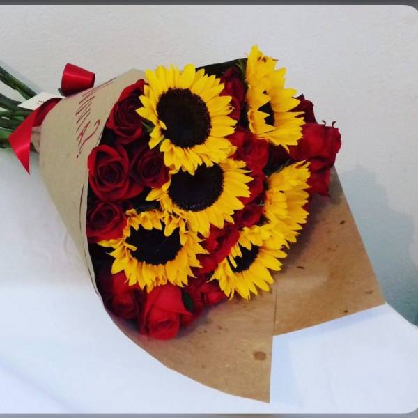 Bouquet of red roses and yellow sunflowers wrapped in brown paper