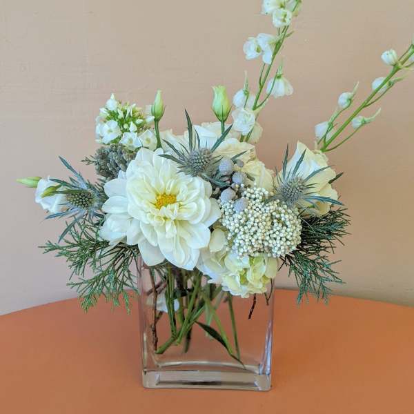 White floral arrangement in a clear square vase