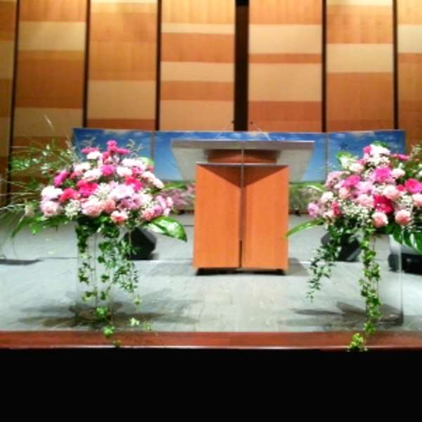 Two pink and white floral arrangements flank a podium on a stage