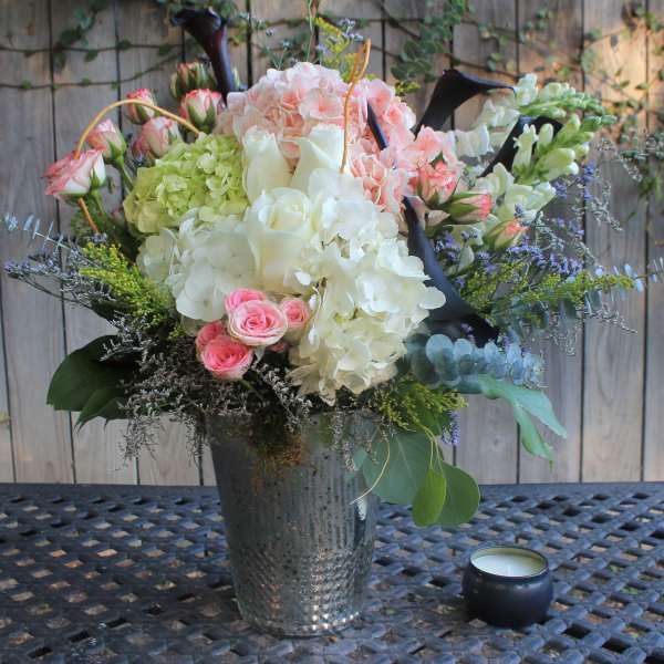 Mixed bouquet of pink, white, and green flowers in a metal vase