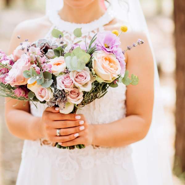 Bride holding a pastel bouquet of roses and mixed flowers