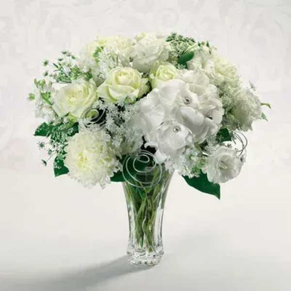 White rose and carnation arrangement in a clear glass vase with silver wire accents