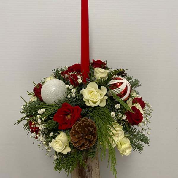 Holiday centerpiece with a red taper candle, roses, and ornaments