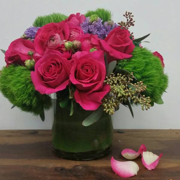 Pink roses and purple flowers in a green glass vase with bright green accents