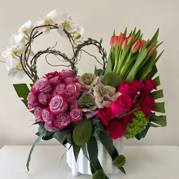 Pink roses and white orchids in a white vase with tulips