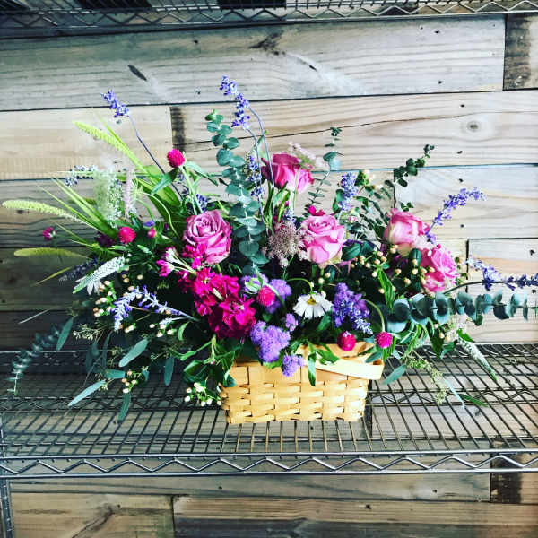 Basket arrangement of pink roses and purple flowers