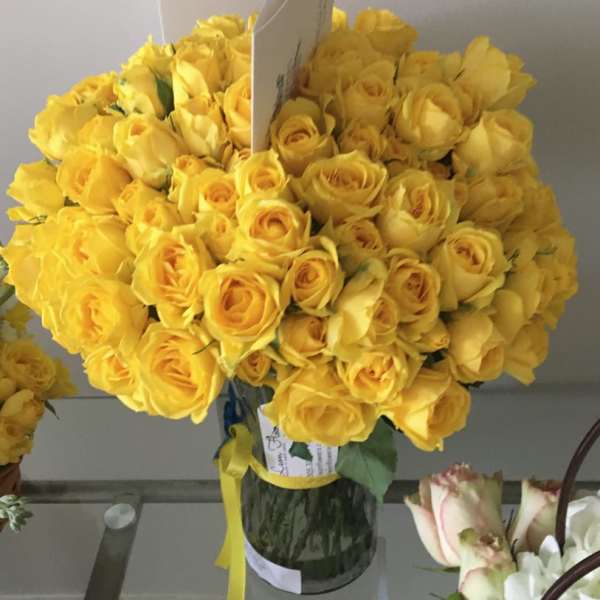 Bouquet of yellow roses in a glass vase with a ribbon