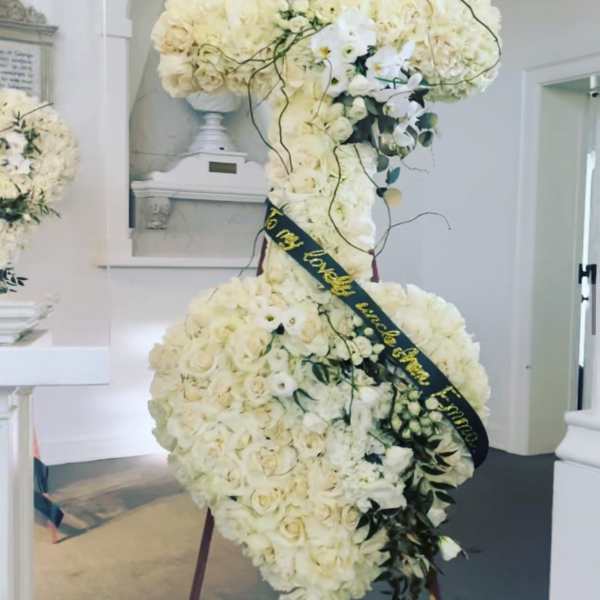 Large white floral standing spray with a black ribbon sash