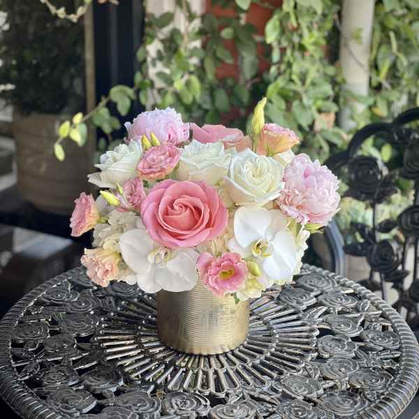 Pink and white floral arrangement in a gold vase