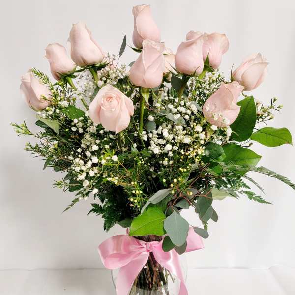 Pink roses in a glass vase with baby's breath and a pink ribbon