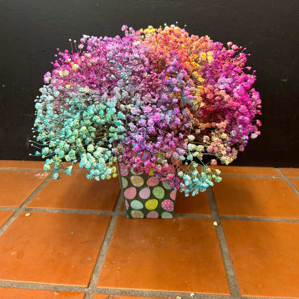 Compact arrangement of rainbow-dyed tiny blooms in a patterned square container