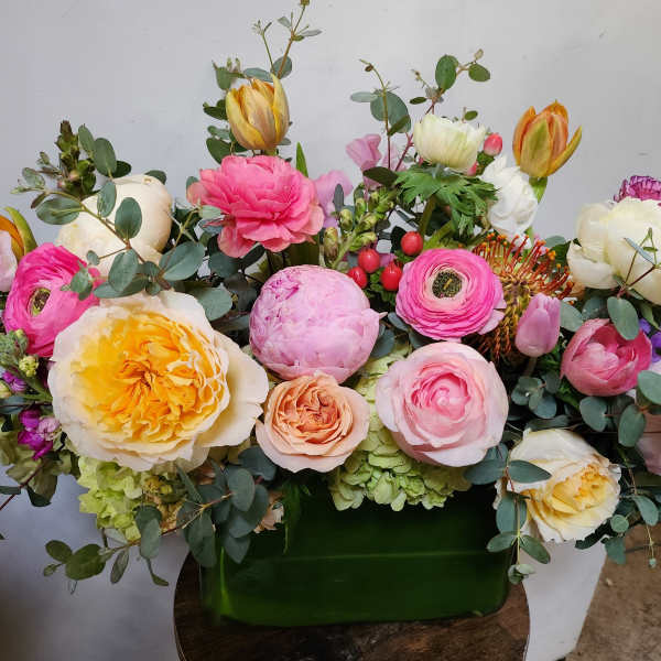 Mixed bouquet of pink, white, and yellow flowers in a green container