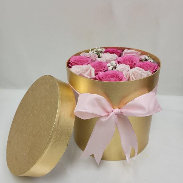 Round gold hatbox of pink and pale roses with lid and pink ribbon bow.
