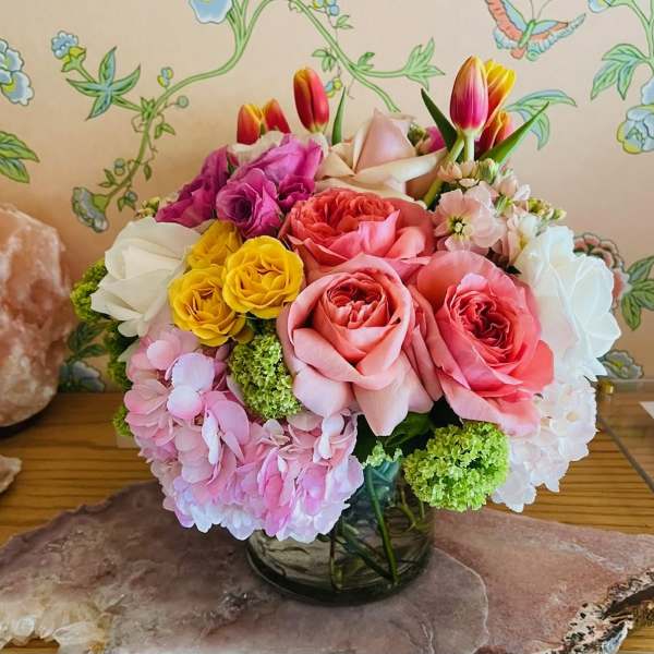 Colorful bouquet of roses, hydrangeas, and tulips in a glass vase