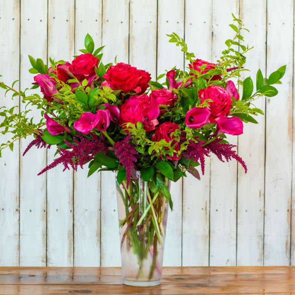 Pink roses and calla lilies in a clear glass vase