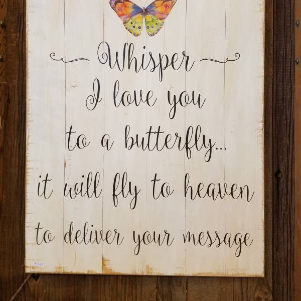 Wooden memorial sign with a colorful butterfly and the words "Whisper I love you"