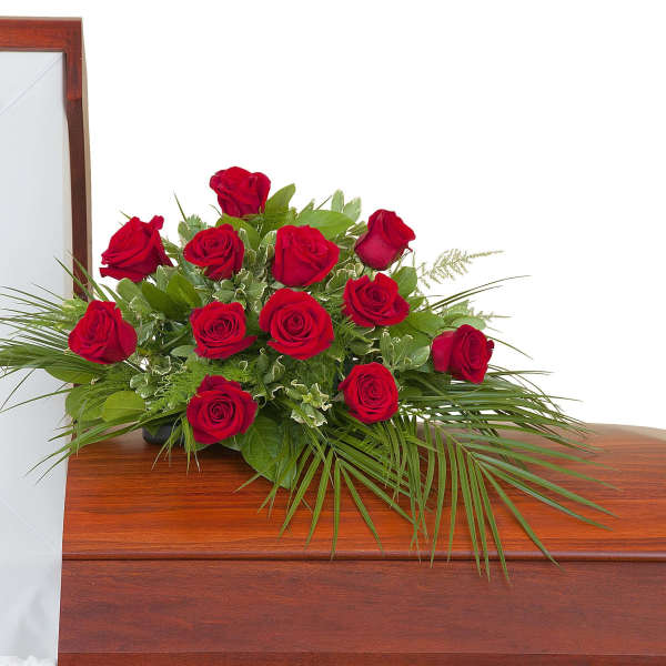 Red rose casket spray arranged on a polished wooden casket