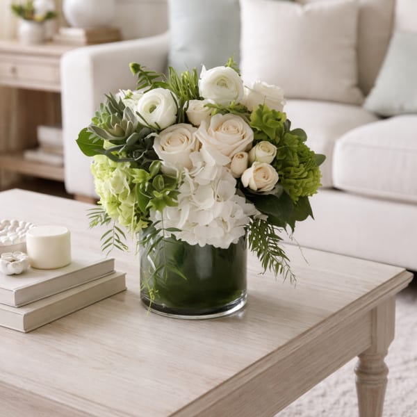 White and green floral arrangement in a glass vase on a coffee table