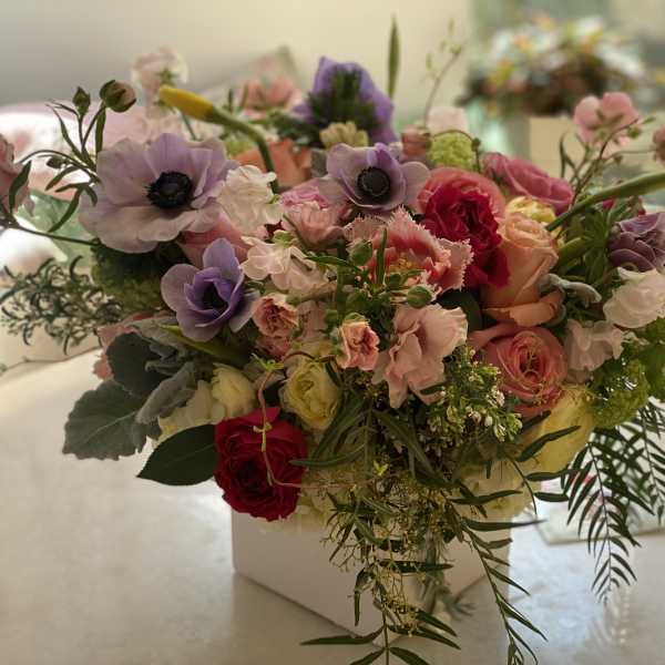Mixed bouquet of pink, purple, and red flowers in a white vase