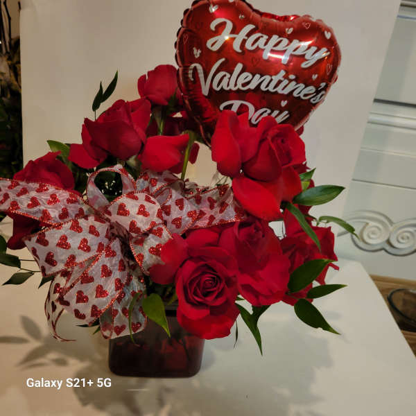Red roses in a vase with a heart-shaped Valentine balloon and heart ribbon