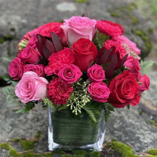 Pink and red rose arrangement in a square glass vase