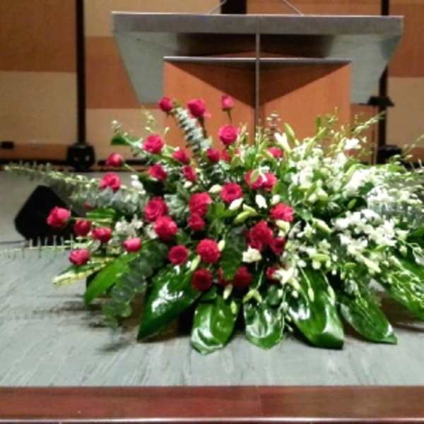 Large red and white floral spray with glossy green leaves arranged in front of a podium.
