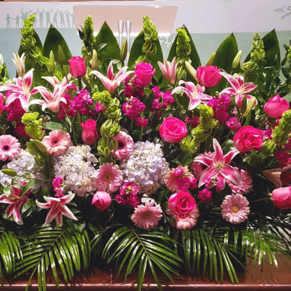 Large pink and white floral arrangement with roses, lilies, hydrangeas and gerberas in a low, wide display