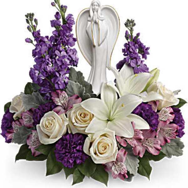 Purple and white floral arrangement with an angel figurine