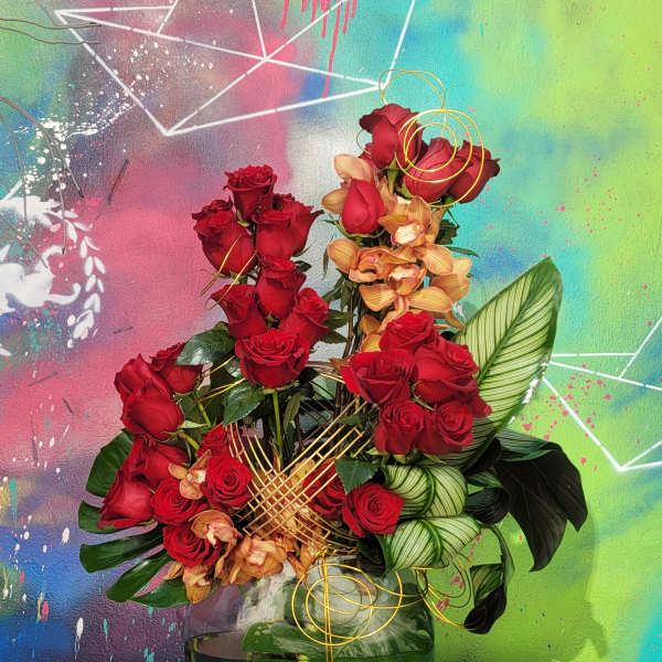 Red roses and peach orchids in a glass vase with gold wire accents