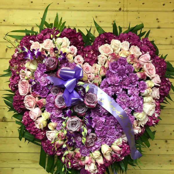 Heart-shaped floral tribute with pink and purple roses and hydrangeas